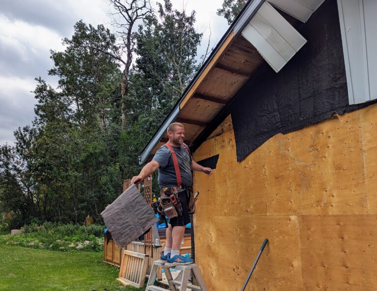 Business owner Shayne McCoy removing old exterior paper on the job